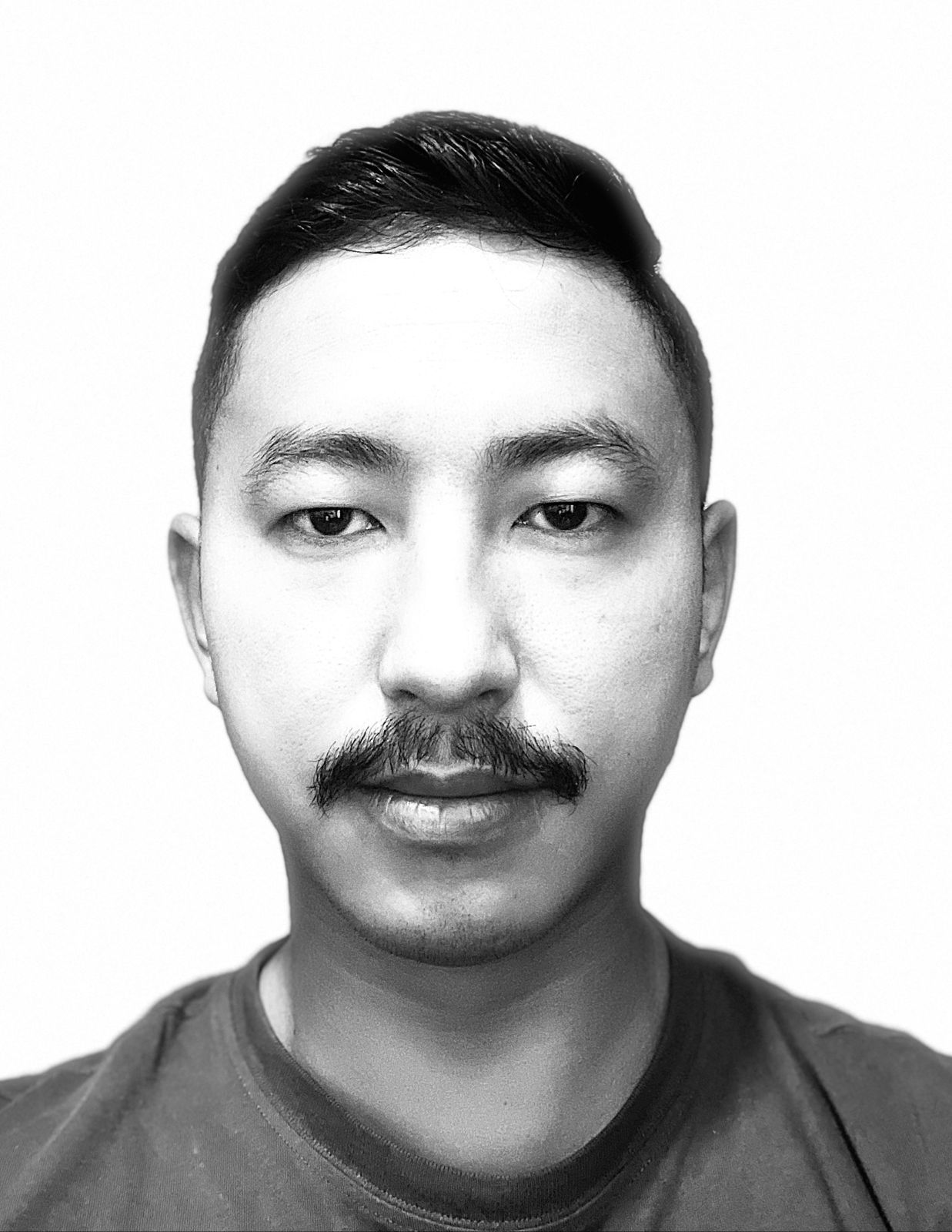 Black and white profile picture of a young man with moustache.