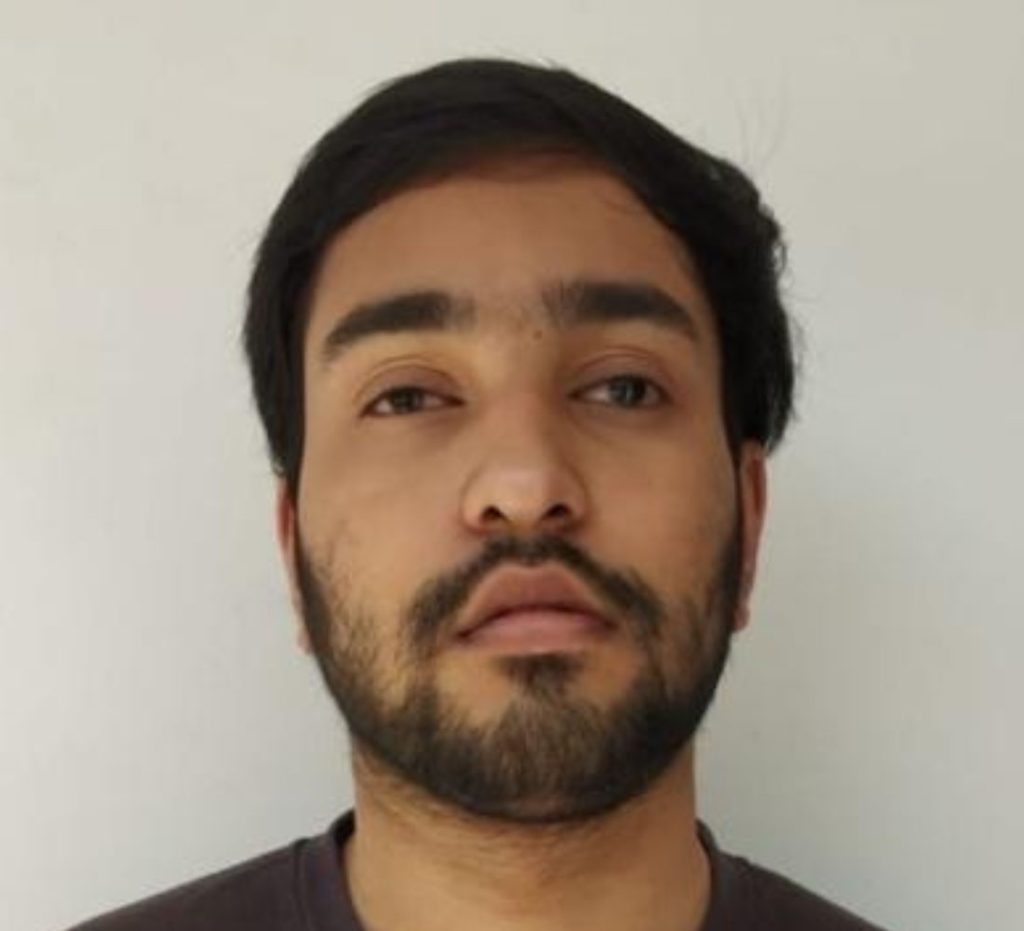 Headshot of Sachin. He is wearing a black T-shirt and standing against a light-coloured wall.